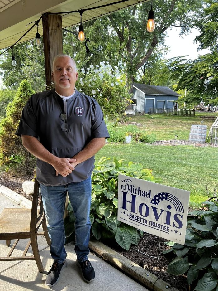 Michael Hovis standing on his porch next to a Hovis yard sign