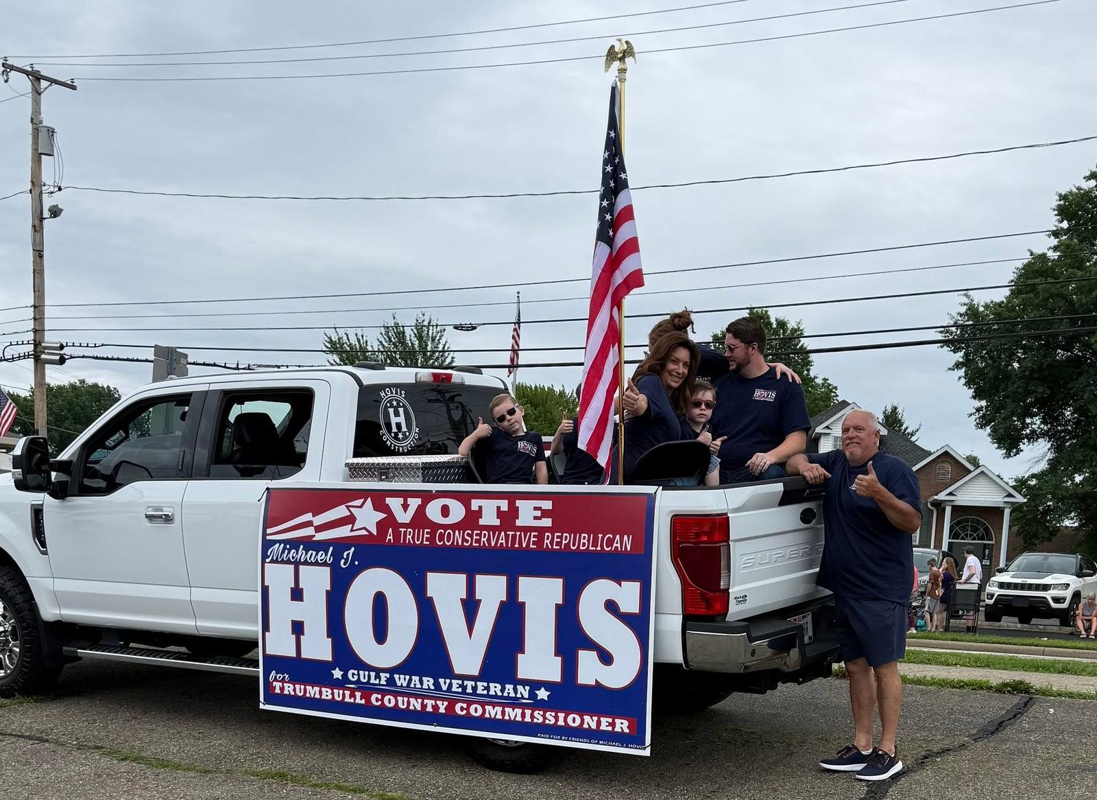 The Hovis family riding in a parade with a campaign banner and American flag