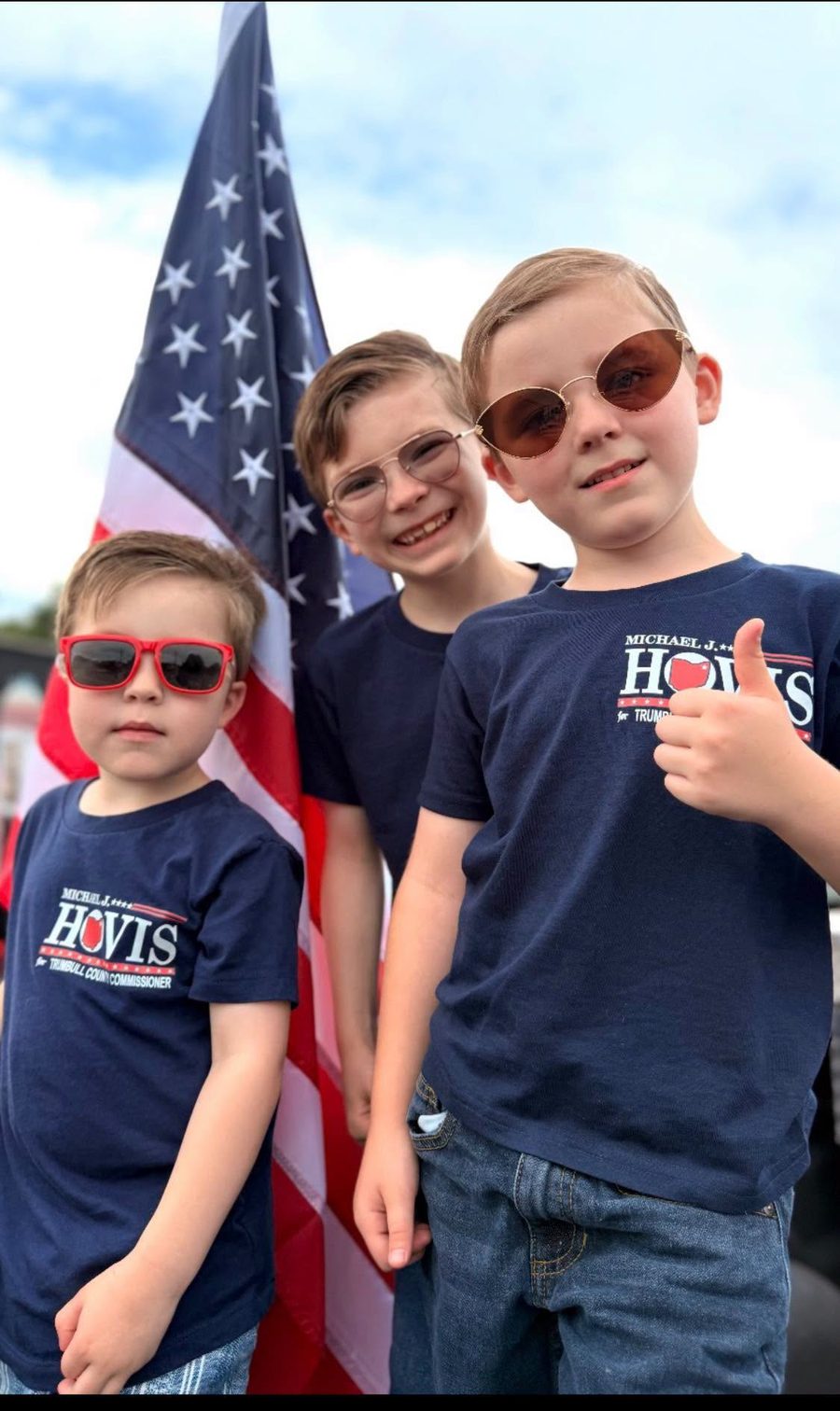 Three of Michael's grandsons in navy HOVIS campaign shirts in front of an American flag